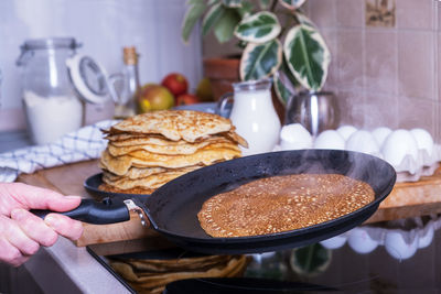 Housewife woman bakes pancakes for breakfast. home cooking pancakes in pan on glass-ceramic stove 