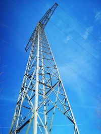 Low angle view of electricity pylon against blue sky