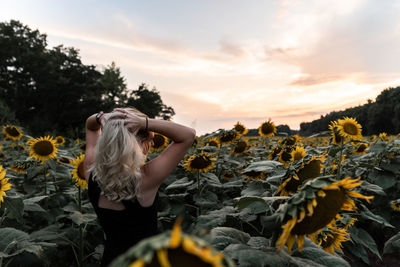 Rear view of woman standing in park against sky during sunset