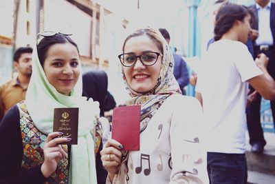 Portrait of smiling young women holding passports while standing outdoors