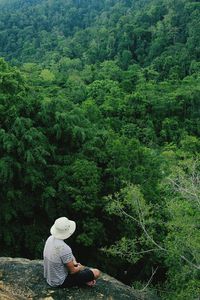 High angle view of man sitting on cliff against trees