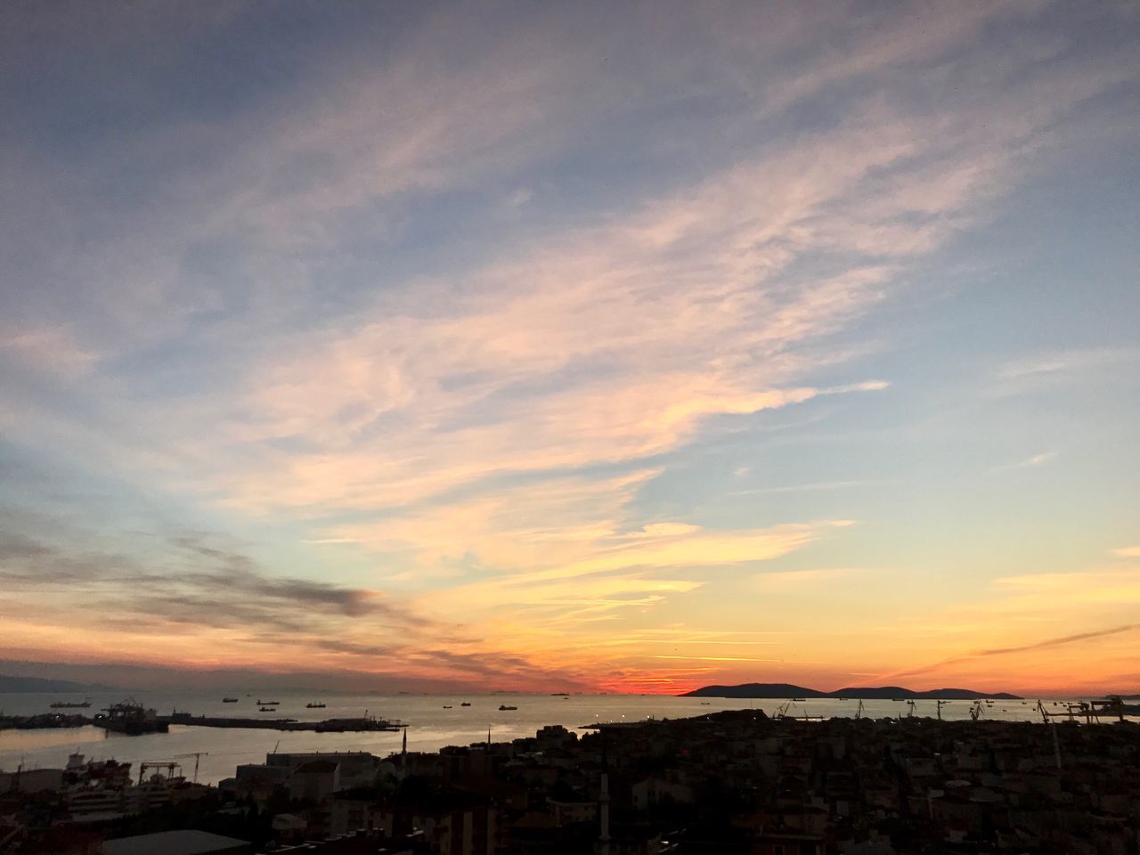 sunset, water, sky, tranquil scene, built structure, architecture, scenics, tranquility, cloud - sky, sea, cloud, atmosphere, nature, beauty in nature, orange color, calm, outdoors, dramatic sky, harbor, distant, no people, ocean, multi colored, atmospheric mood, moody sky