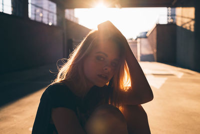 Portrait of beautiful young woman sitting in corridor