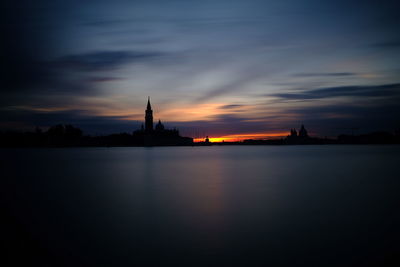 Silhouette of cathedral against cloudy sky during sunset