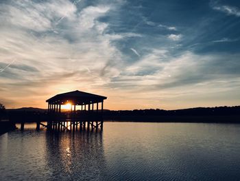 Silhouette gazebo in lake against sky during sunset