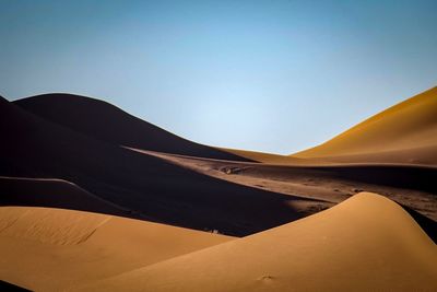 Low angle view of sand dunes against clear sky