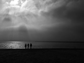 Silhouette people on beach against sky