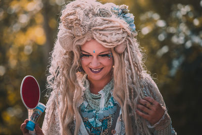 Smiling woman with headdress and make-up looking down