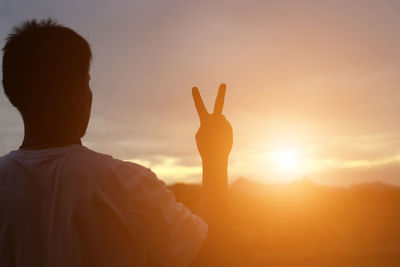 Rear view of silhouette man standing against sky during sunset