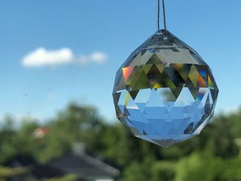 Close-up of ball hanging on glass against sky