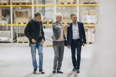 Full length of businesswoman gesturing while discussing with coworkers at industry