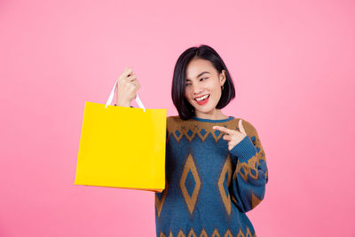 Portrait of a smiling young woman against pink background