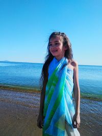 Girl covered with sarong standing on shore at beach 