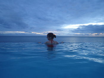 Rear view of woman sitting in swimming pool