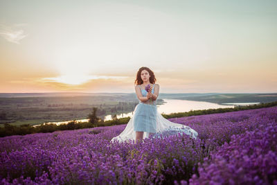 A beautiful young girl against the sunset and a beautiful sky in a lavender field. 