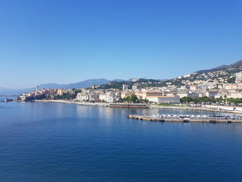 Townscape by sea against clear blue sky