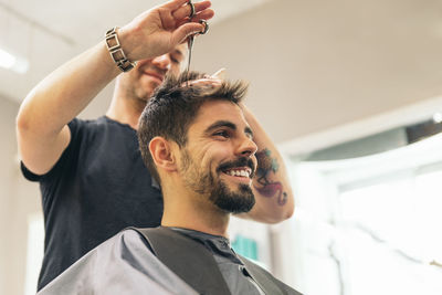 Low angle view of smiling barber and customer in salon
