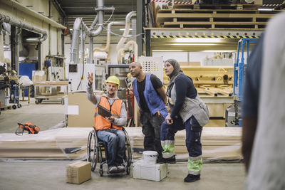 Carpenter with disability explaining to colleagues in warehouse
