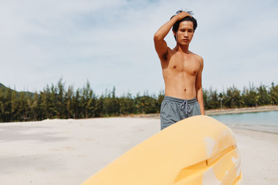 Rear view of shirtless young woman standing at beach