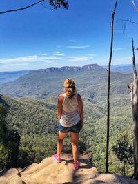 Rear view of woman standing on mountain against sky