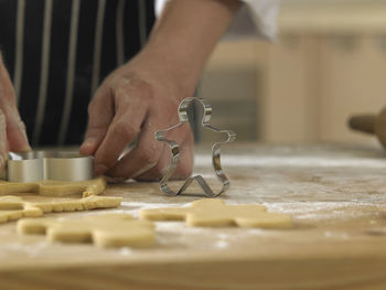 Midsection of chef cutting dough with pastry cutter at table