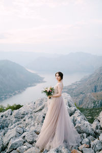 Woman with umbrella on mountain against sky