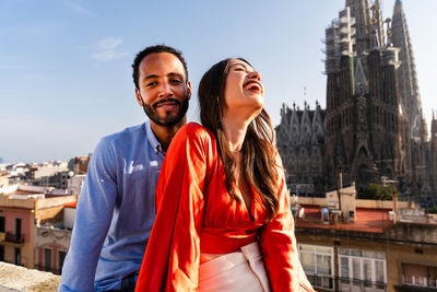 Portrait of smiling friends standing against buildings