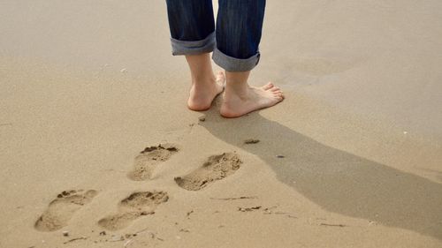 Low section of man standing on sand