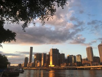 River by buildings against sky during sunset