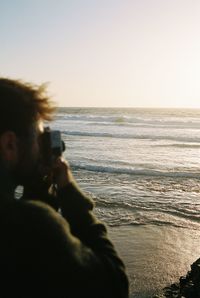 Man photographing sea against sky