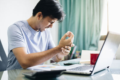 Young man using mobile phone while sitting on table