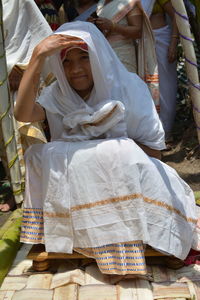 Portrait of bride wearing traditional clothing while sitting outdoors