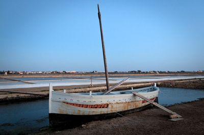 Boat moored at beach against clear blue sky