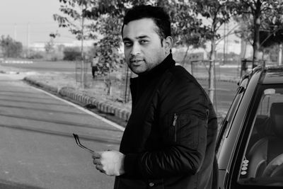 Portrait of young man standing by car