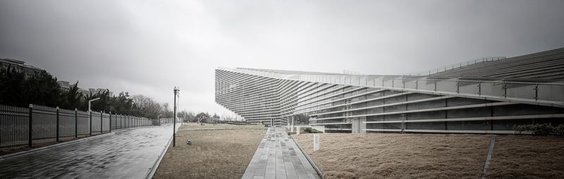 Empty road by buildings against sky