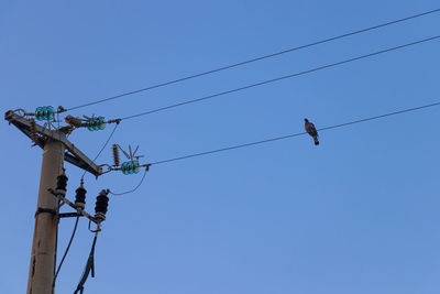 Low angle view of power lines against clear blue sky