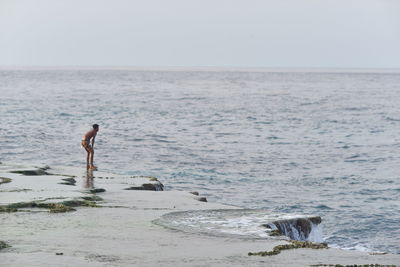 Rear view of man walking on beach against sky