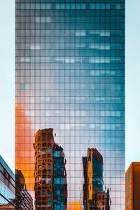 Low angle view of modern glass building against sky