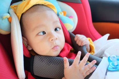 Portrait of cute baby boy sitting in car safety seat