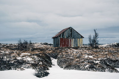 House on snow covered field against sky