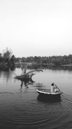 Rear view of man sailing coracle in lake against clear sky