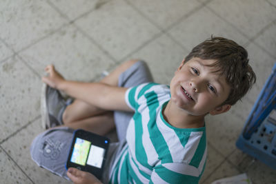 Portrait of boy making face while sitting on tiled floor at home