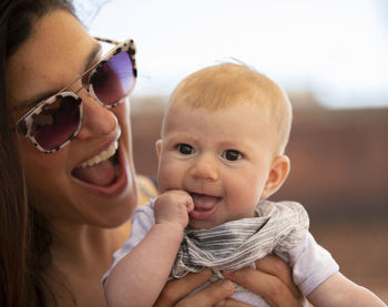 Woman carrying daughter against sky