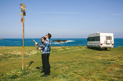 Couple reading sign while holding map on field