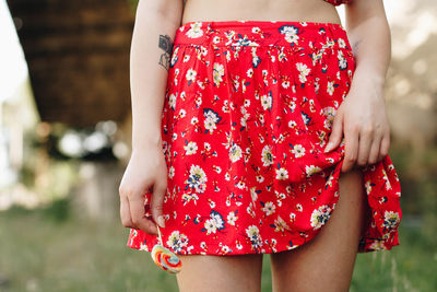 Midsection of woman wearing red skirt holding lollipop