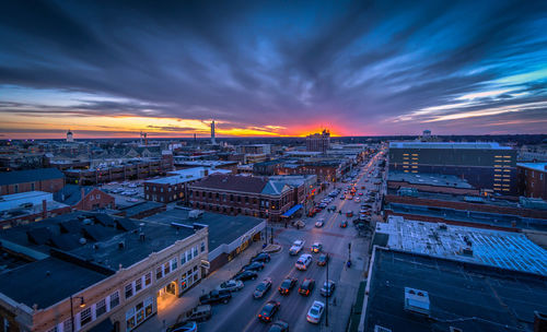 High angle view of street amidst buildings against cloudy sky during sunset