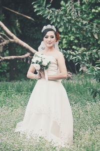 Portrait of young bride standing on field