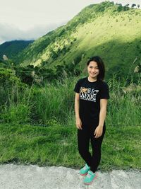 Portrait of smiling young woman standing on green landscape