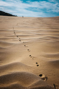 Footprints on sand at beach against sky