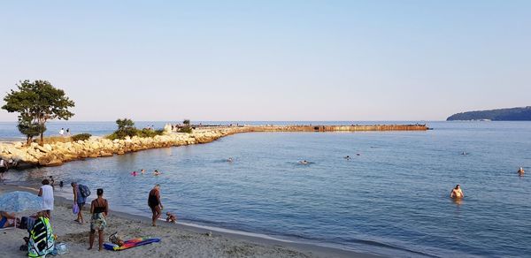 People on beach against clear sky